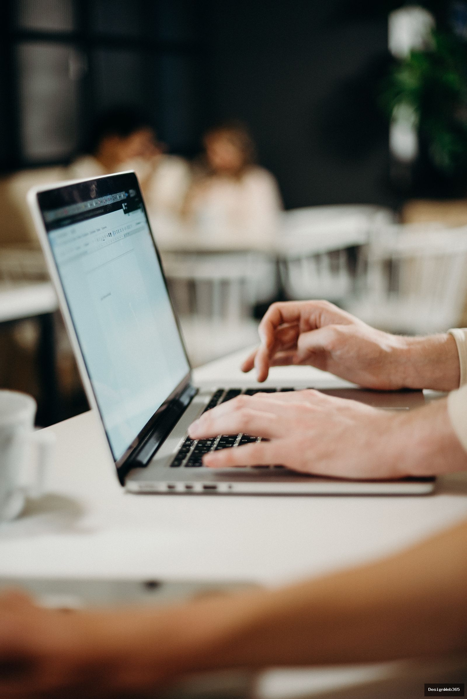 Personne tapant sur un ordinateur portable pour rediger et envoyer un mail dans un espace de travail