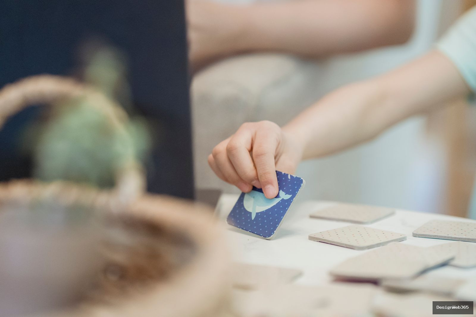 Main d'enfant retournant une carte bleue lors d'un jeu de memoire avec des cartes assorties sur une table