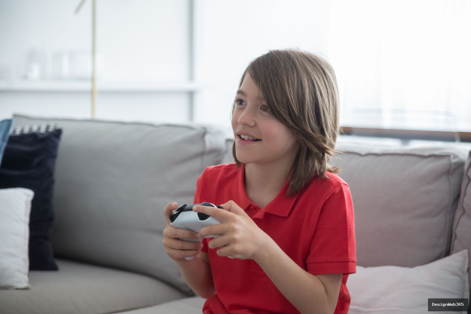 Jeune garcon souriant assis avec une manette de jeu video dans un salon