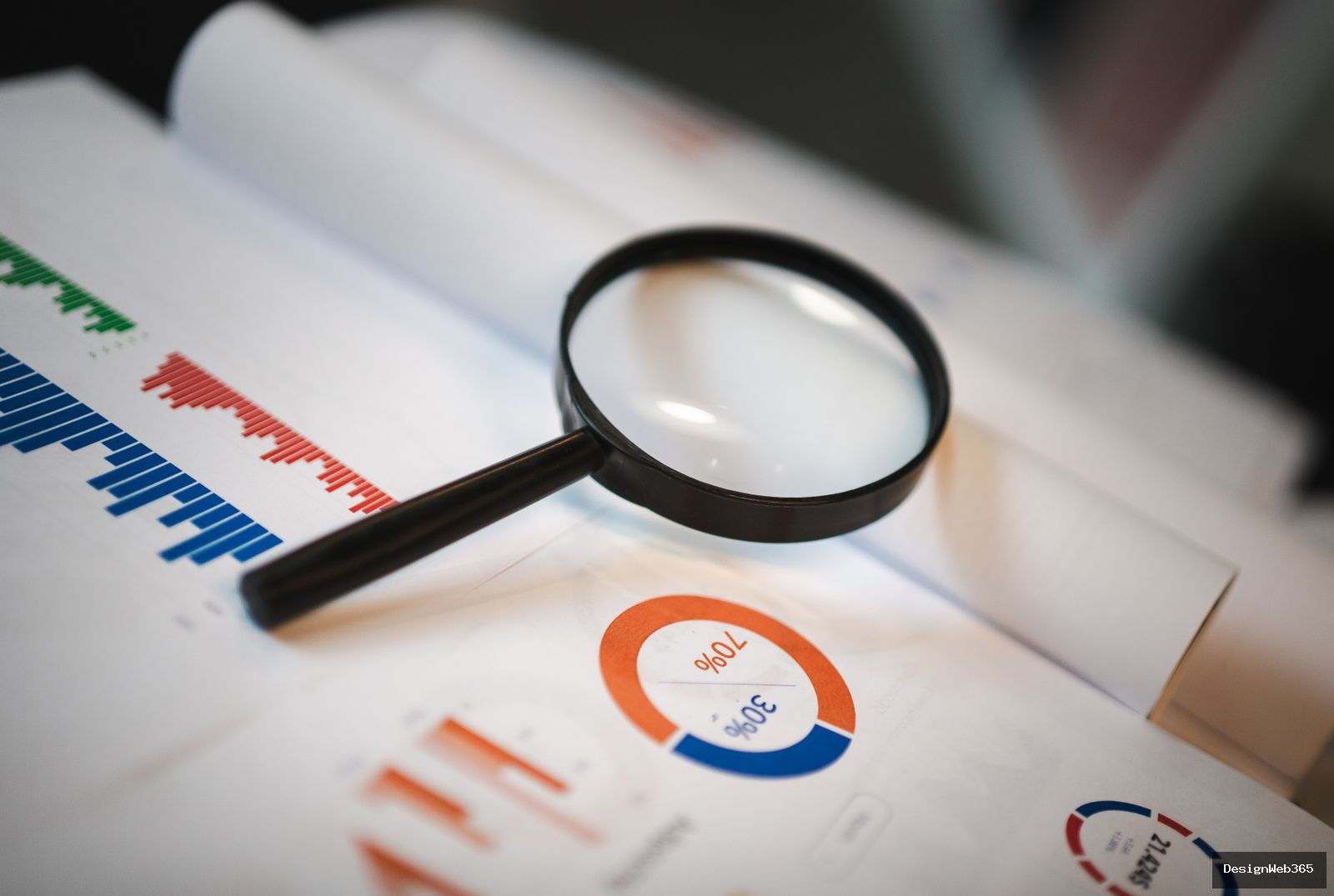Loupe posée sur des graphiques imprimés, symbole de l'audit technique d'un site pour repérer les erreurs de configuration