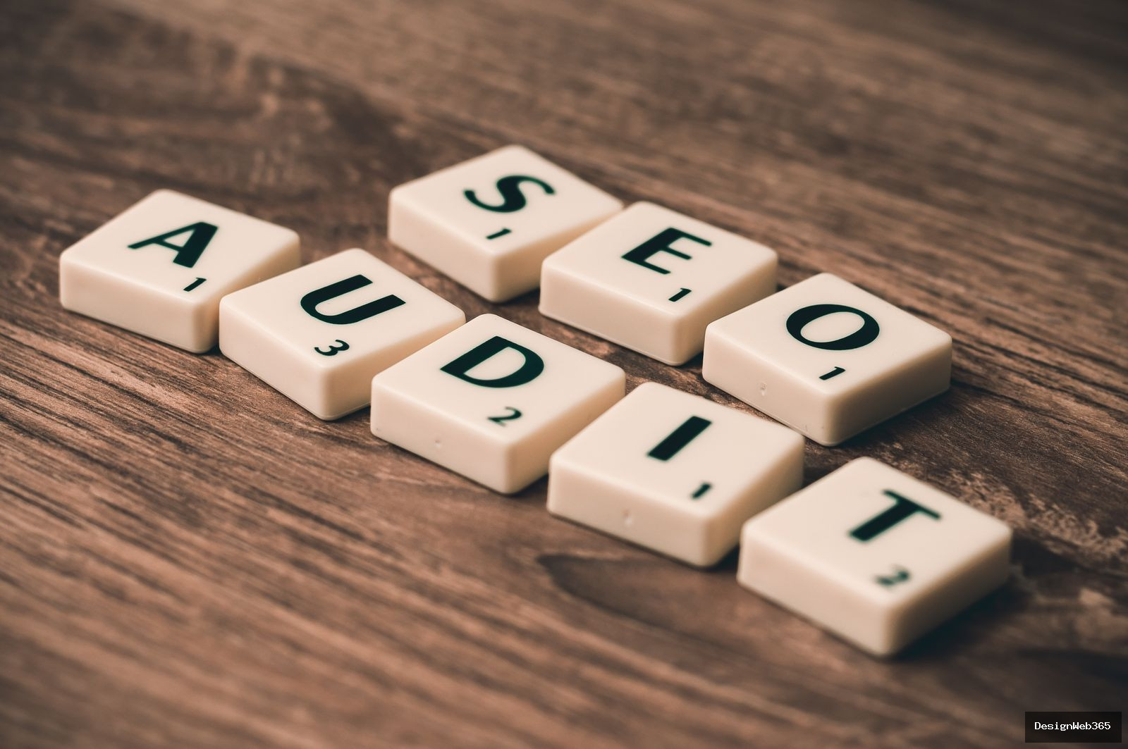 Lettres formant les mots audit et SEO sur une surface en bois, symbole du contrôle de conformité d'un site web