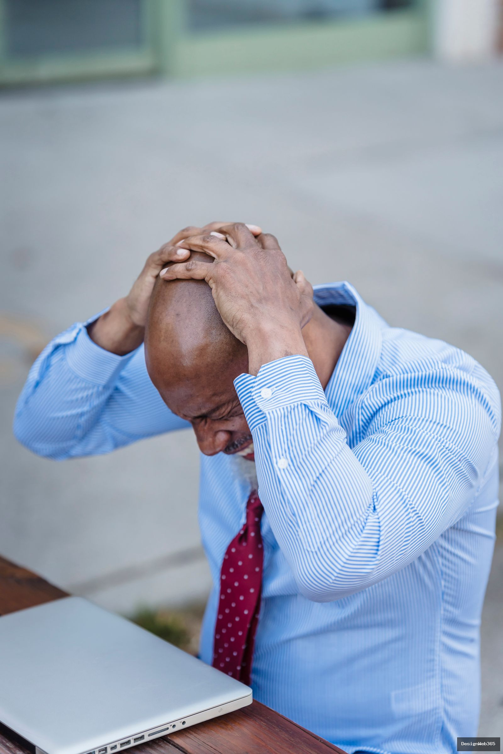 Homme d'affaires frustre se tenant la tete devant son ordinateur portable