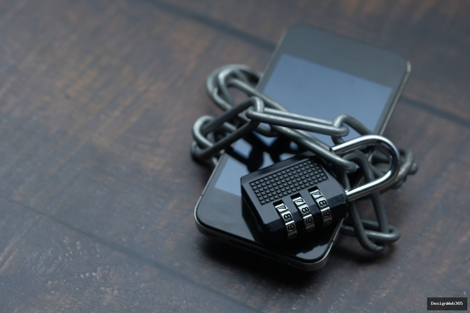 Smartphone entoure d'une chaine et d'un cadenas a code, symbole de restriction de la vie privee