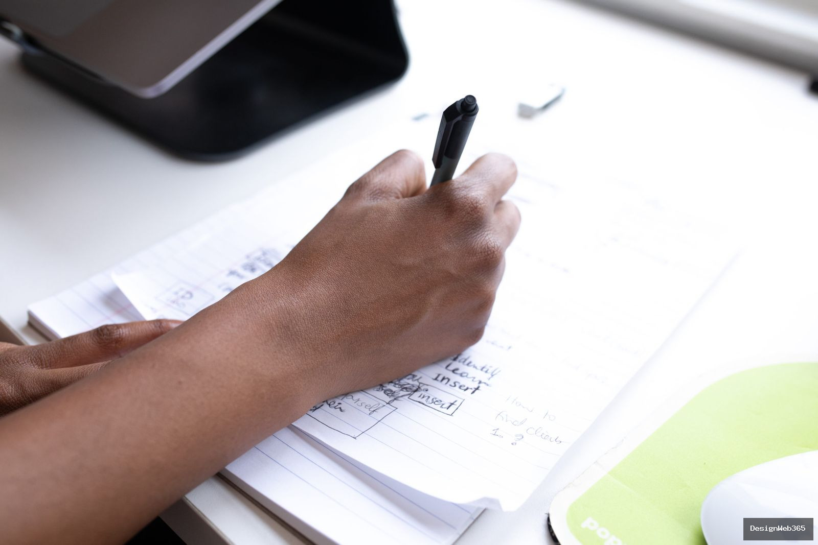 Main tenant un stylo en train d'ecrire une strategie de contenu dans un carnet